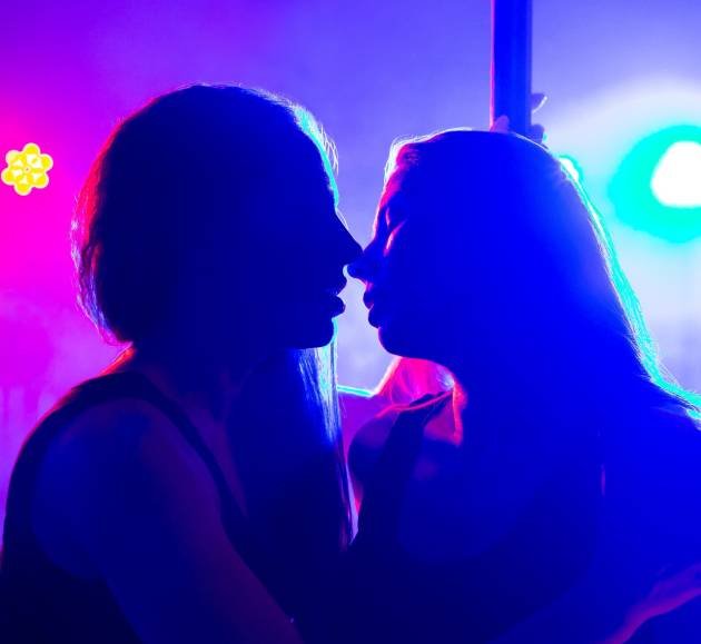 Two young sexy women dance a striptease near the pylon and kiss